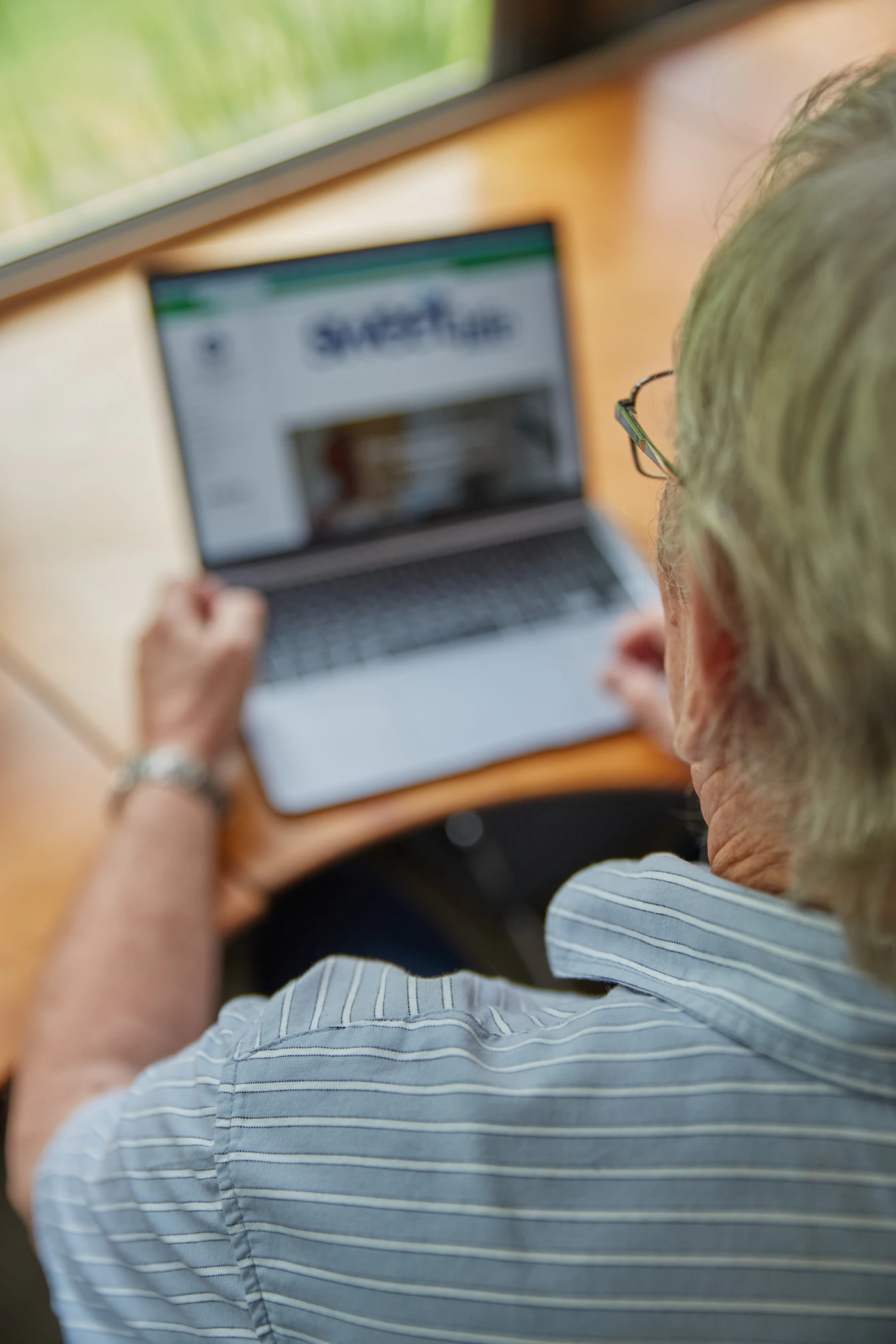 Oudere volwassene bekijkt thuis een laptop