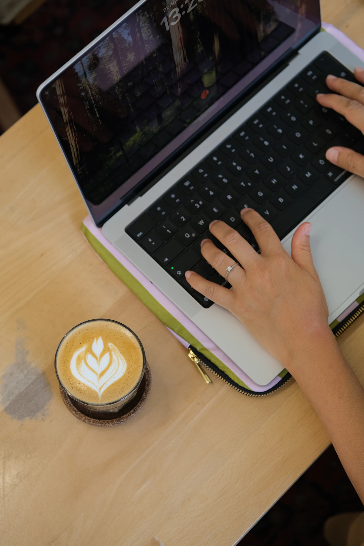 Handen typen op een laptop naast een kop koffie